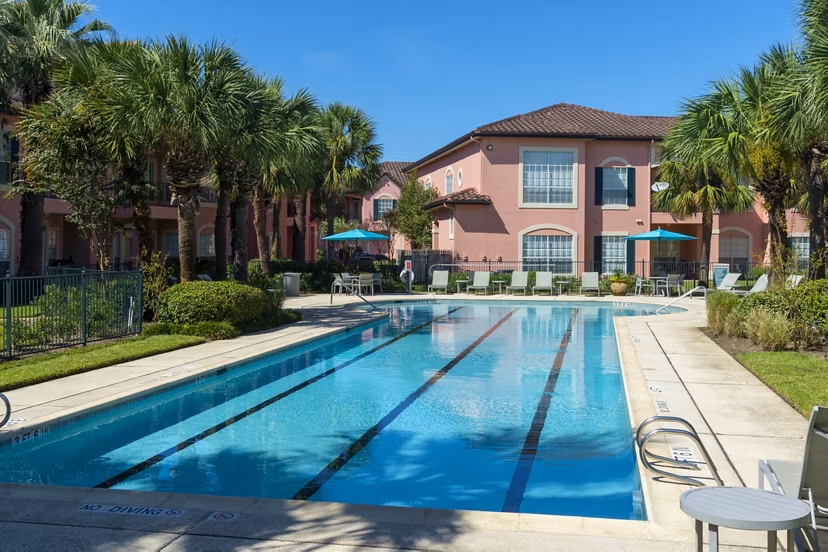 Resort-style pool with palm trees at Las Palmas Apartments, offering luxury outdoor relaxation spaces for residents