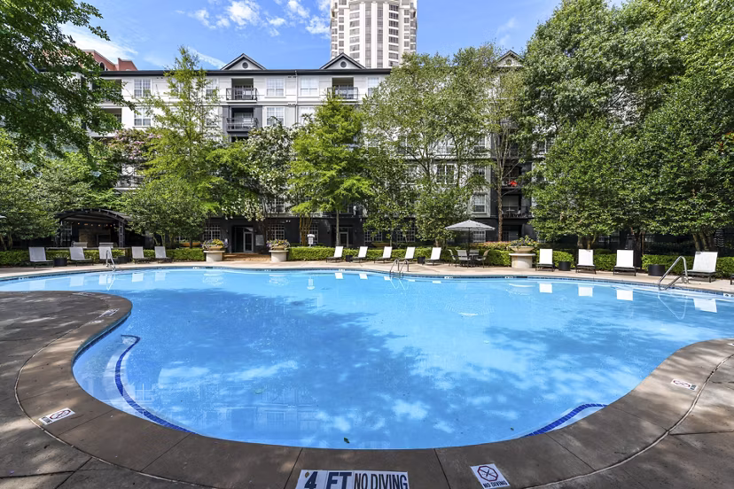 Elegant outdoor pool at Phipps Place Apartments with sun loungers and lush greenery, offering a relaxing retreat for residents