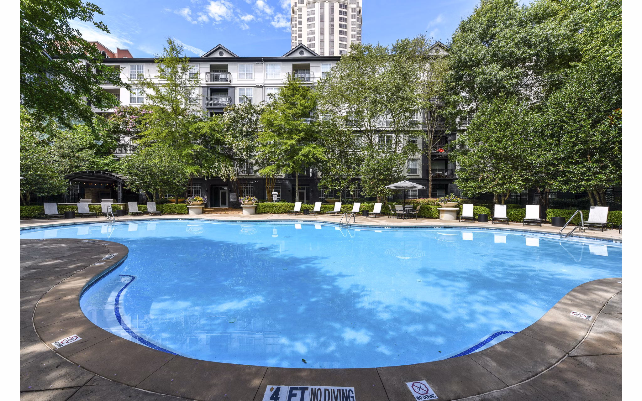 Elegant outdoor pool at Phipps Place Apartments with sun loungers and lush greenery, offering a relaxing retreat for residents