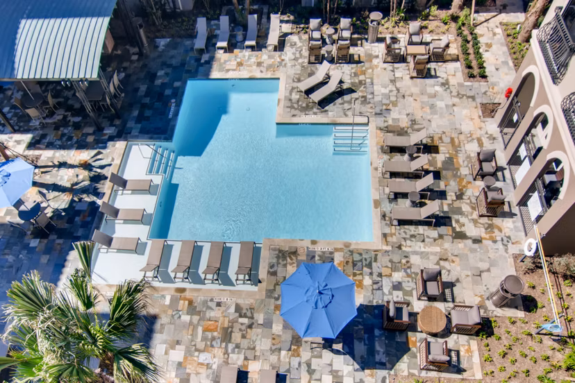 Luxurious poolside oasis at The Caroline Apartments, featuring sun loungers and a sparkling swimming pool for relaxation and leisure