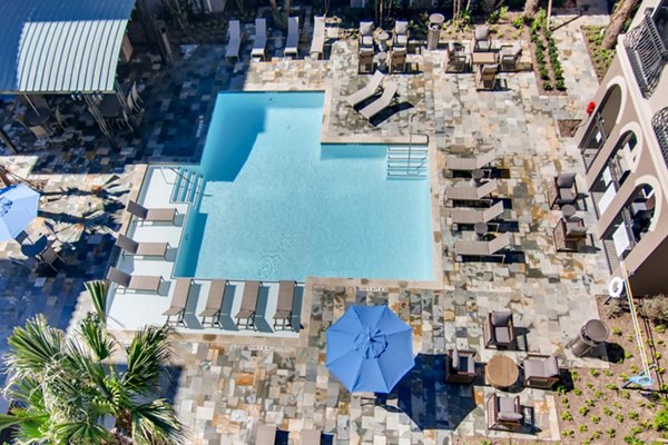 Luxurious poolside oasis at The Caroline Apartments, featuring sun loungers and a sparkling swimming pool for relaxation and leisure