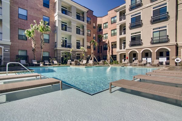 Resort-style pool with luxurious loungers at The Caroline Apartments offering a relaxing oasis for residents