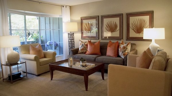 Spacious living room featuring stylish sofa, armchairs, and vibrant wall art in luxury apartment