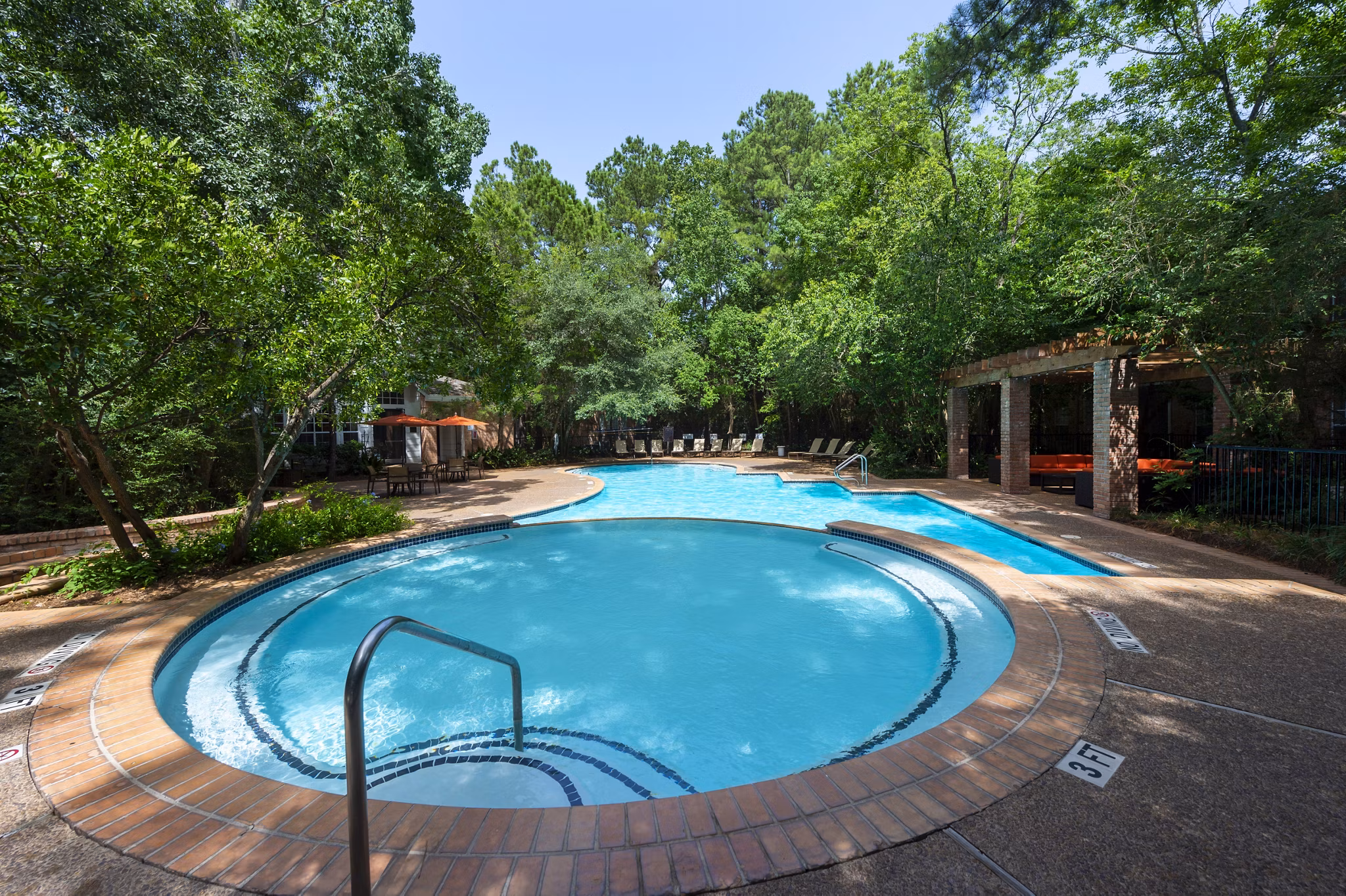 Resort-style pool area at The Park on Memorial Apartments, surrounded by lush landscaping and luxury lounging options
