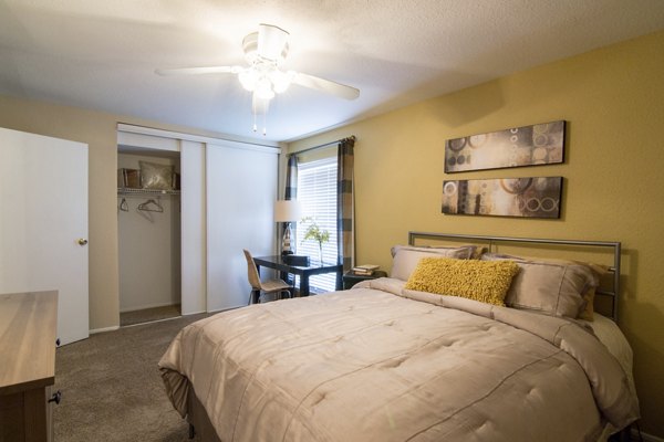 Cozy bedroom with plush bedding at The Pines of Woodforest Apartments, featuring ample natural light and modern furniture