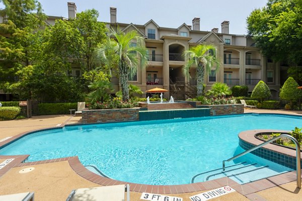 Luxurious swimming pool at The Post Oak at Woodway Apartments with lounge chairs and lush landscaping