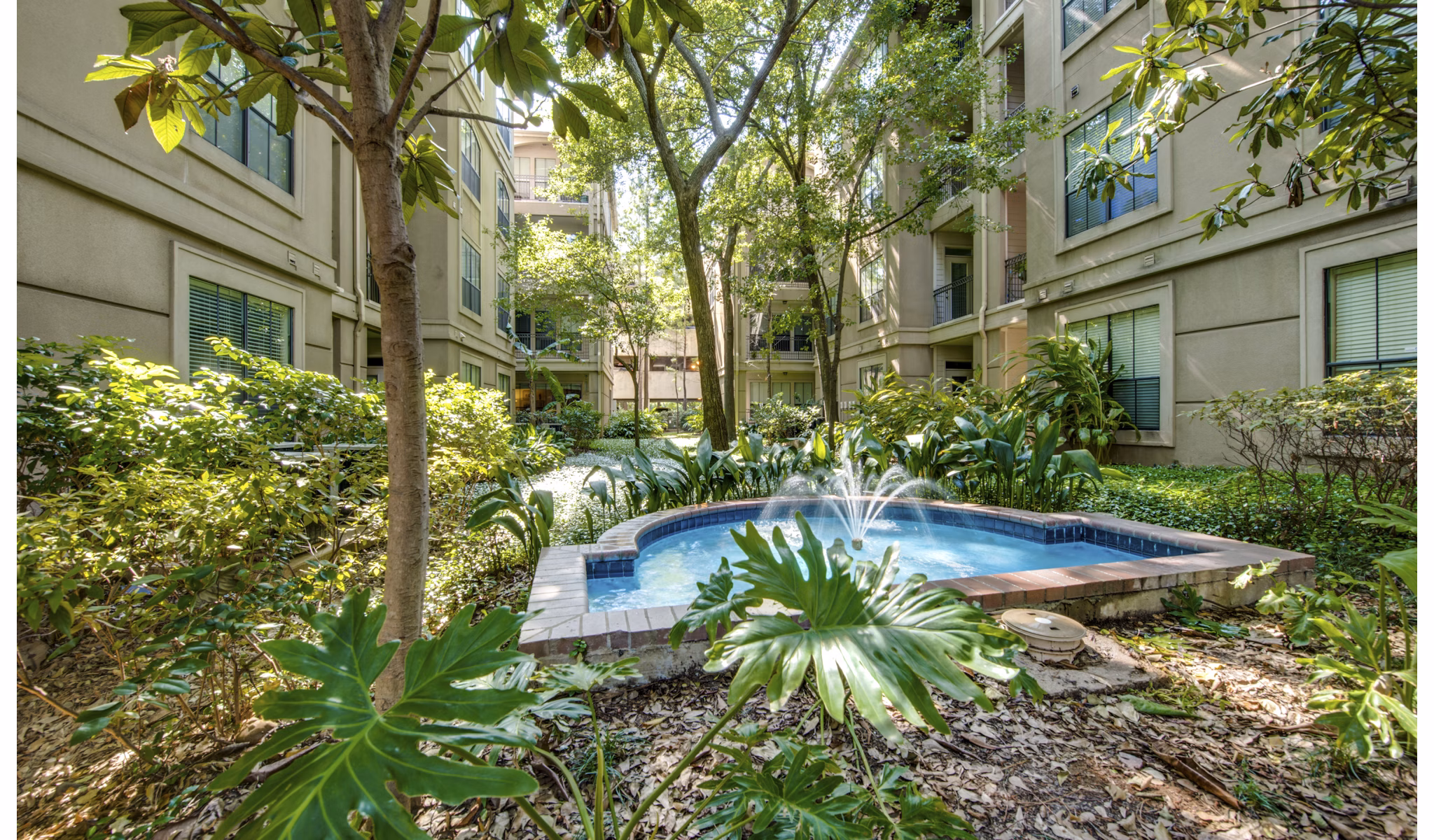Relaxing courtyard with lush landscaping at The Post Oak at Woodway Apartments