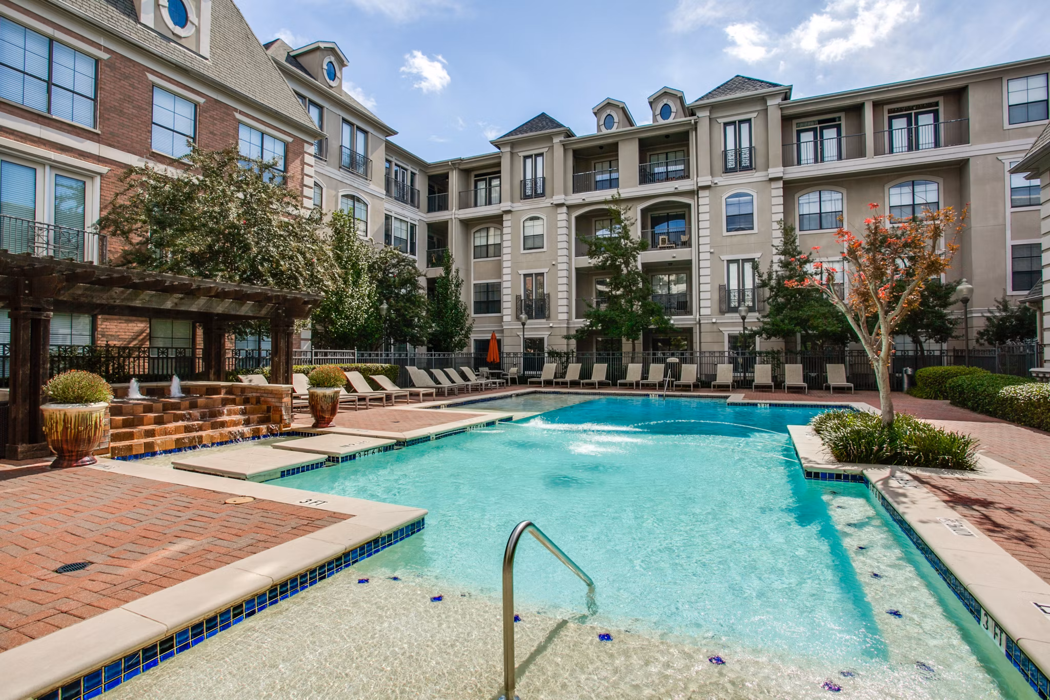 Luxurious outdoor pool at Renaissance at Preston Hollow Apartments with sleek lounge seating and palm trees