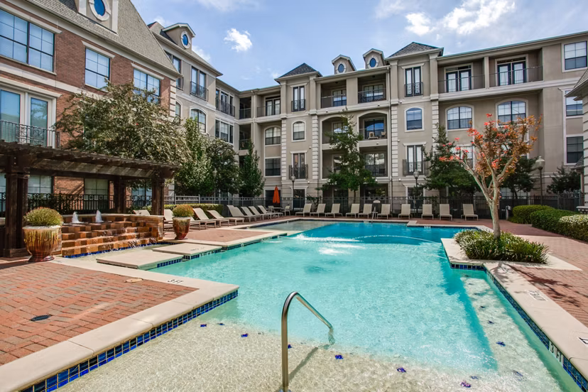 Luxurious outdoor pool at Renaissance at Preston Hollow Apartments with sleek lounge seating and palm trees