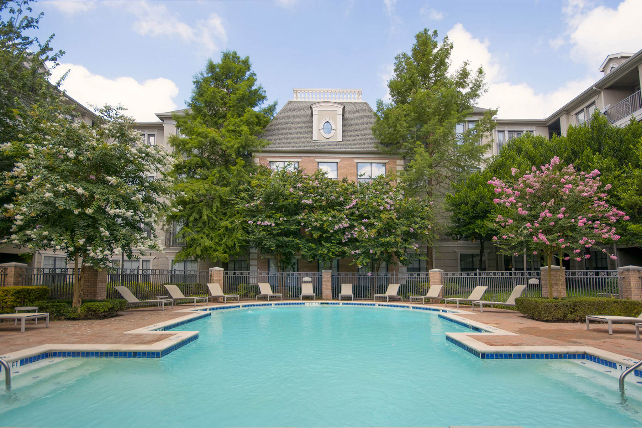 Outdoor swimming pool with lounge chairs at Renaissance at Preston Hollow Apartments