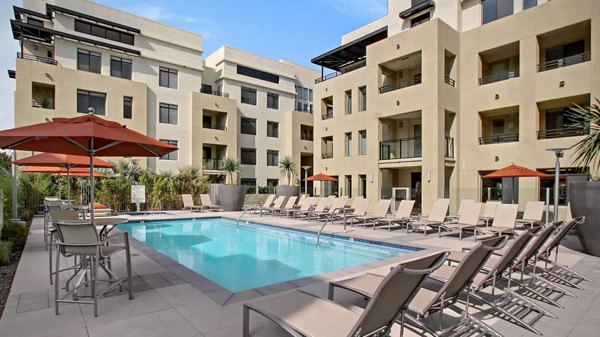 Modern outdoor pool with sun loungers at Westgate Apartments