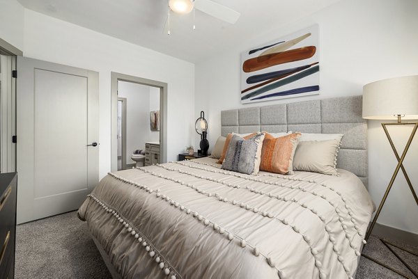 Cozy bedroom with modern design at The Easley Apartments, featuring natural lighting and sleek furnishings for a comfortable living experience