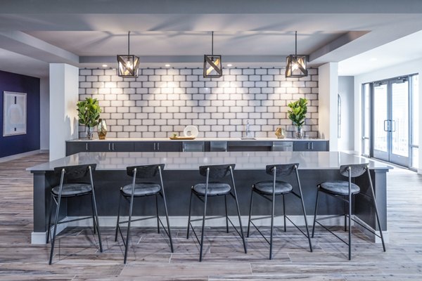 Contemporary kitchen in clubhouse at Prose Hardy Yards Apartments featuring island seating and stainless steel appliances