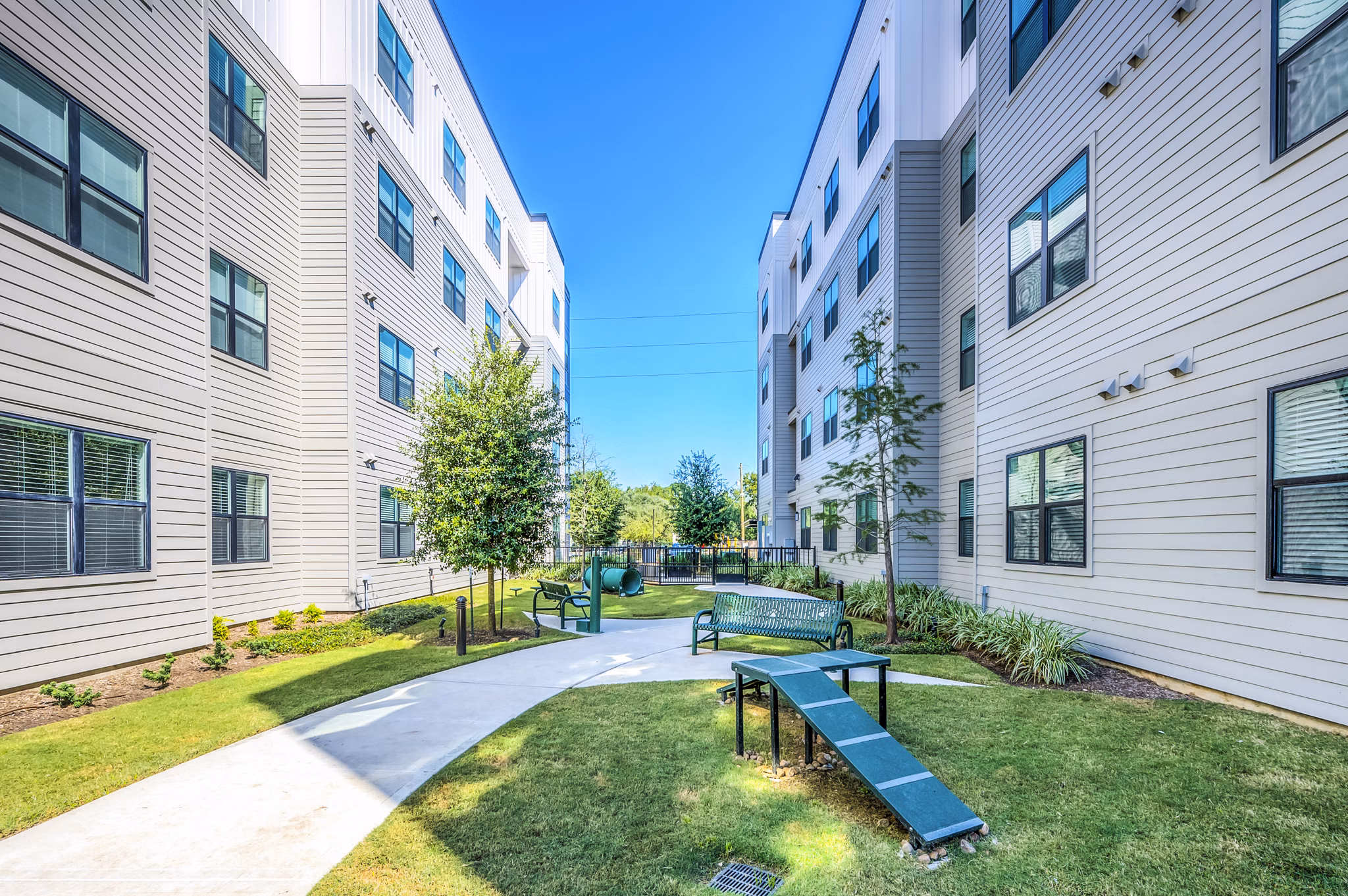 Dog park at Prose Hardy Yards Apartments featuring green lawn and agility equipment for outdoor pet enjoyment