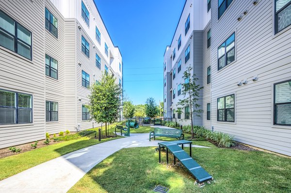 Dog park at Prose Hardy Yards Apartments featuring green lawn and agility equipment for outdoor pet enjoyment