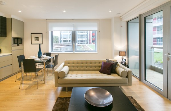 Elegant living room with a cream sofa, colorful cushions, and large windows providing ample natural light and a view of the outdoors.