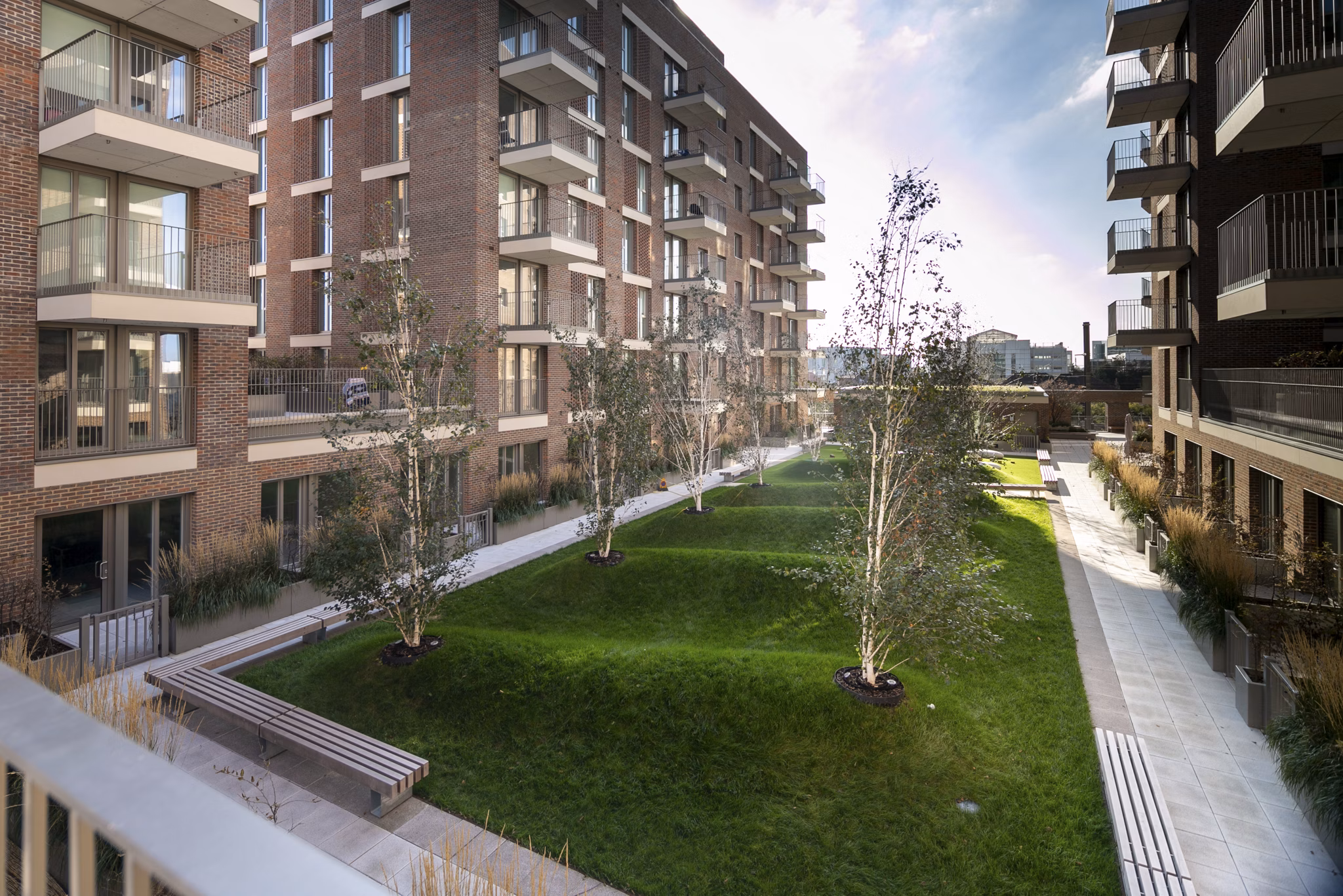 Beautifully landscaped courtyard at Fizzy Hayes, featuring green lawns and trees surrounded by modern apartments.