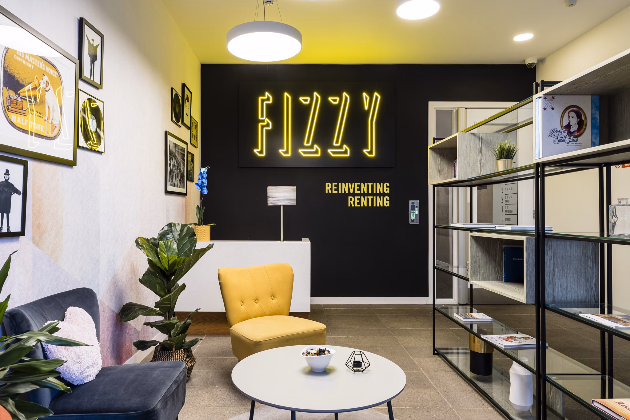 Cozy community lounge area with modern furnishings, a vibrant 'Fizzy' neon sign, and comfortable seating options.