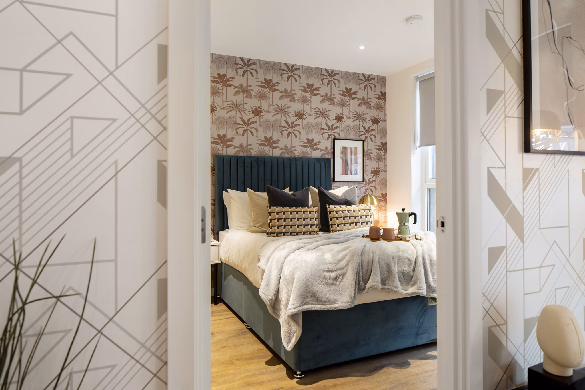 Elegant bedroom with a teal velvet bed, decorative cushions, and soft ambient lighting creating a cozy atmosphere.