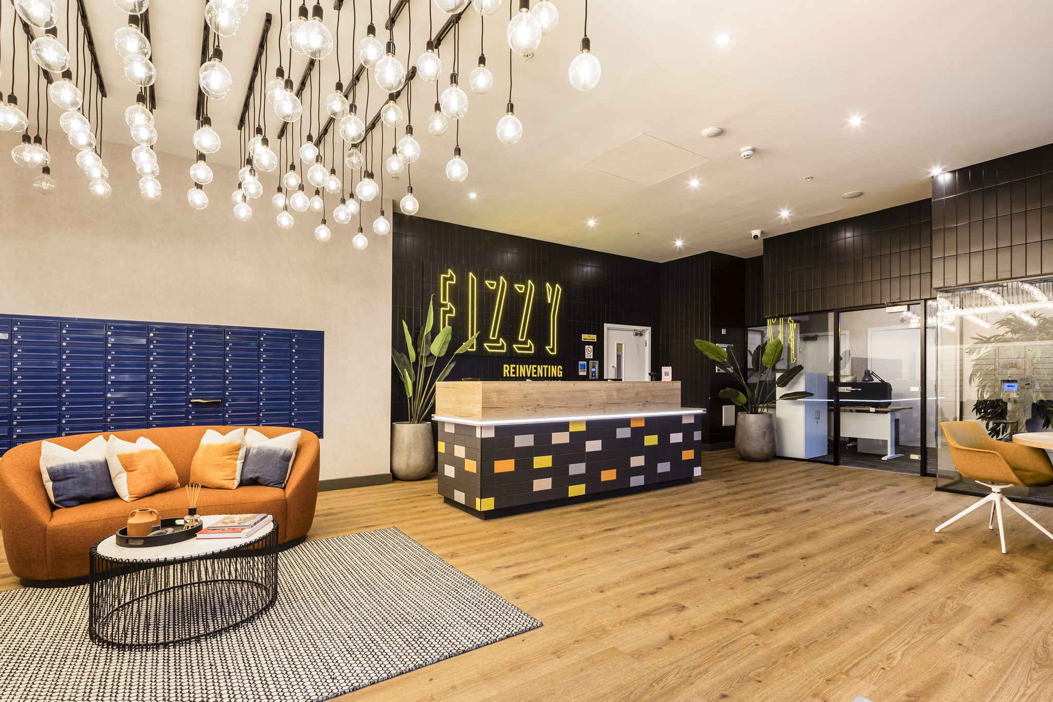 Contemporary community lounge area featuring a vibrant 'Fizzy' sign, comfortable seating, and a well-lit open space.