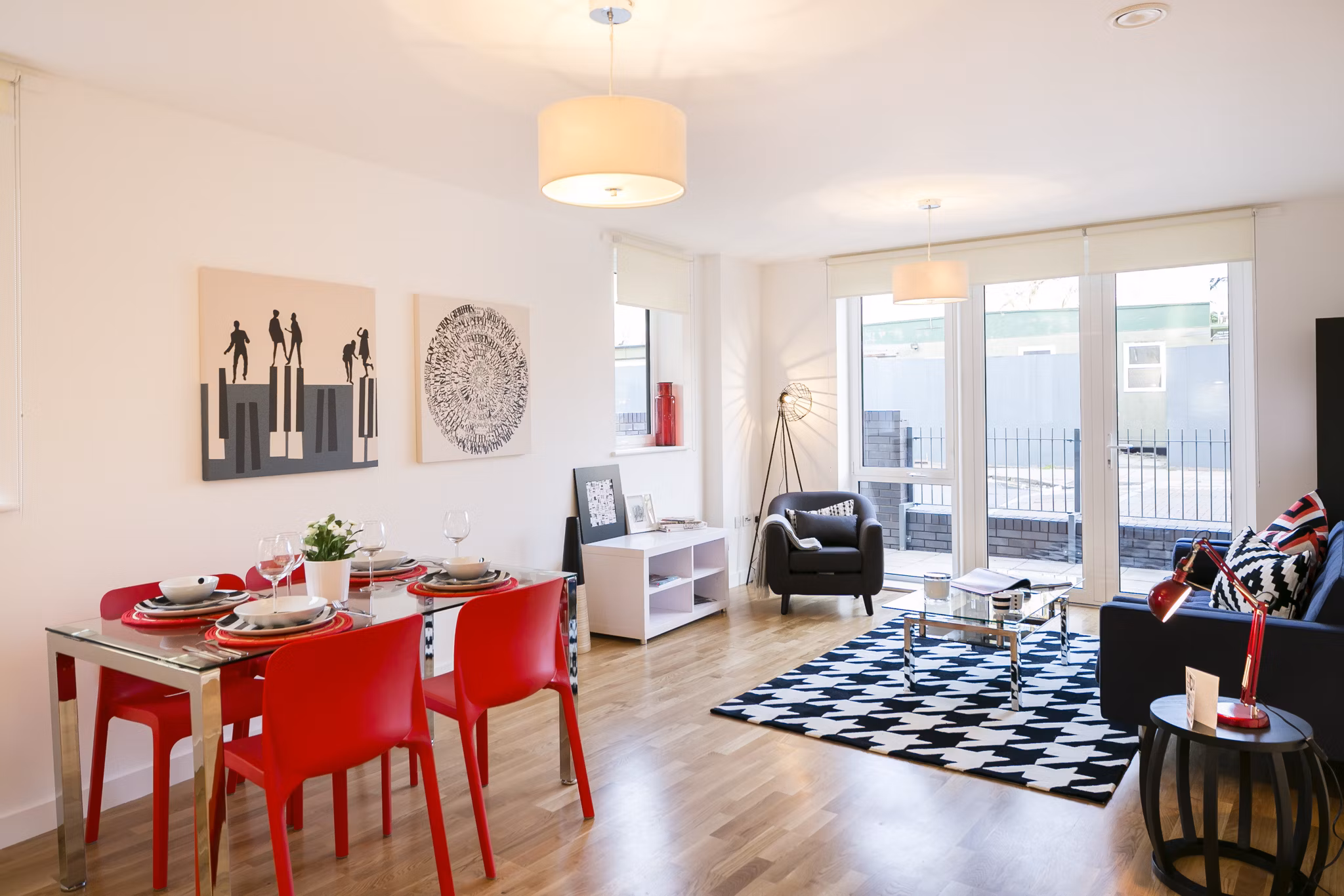 Stylish dining and living area at Fizzy Stepney Green featuring a red dining set, black-and-white patterned rug, and modern decor.