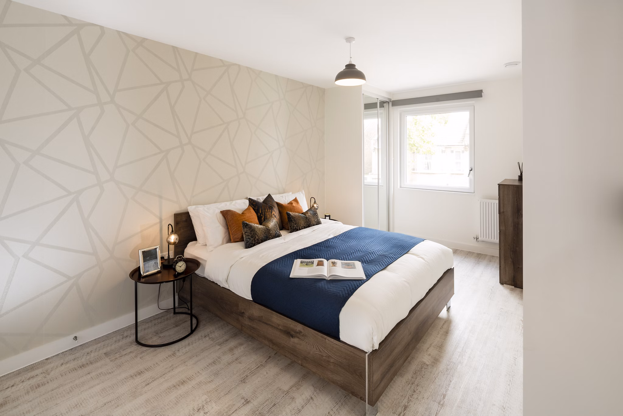 Comfortable bedroom at Fizzy Walthamstow with a neatly made bed, geometric wall design, and natural light from the window.