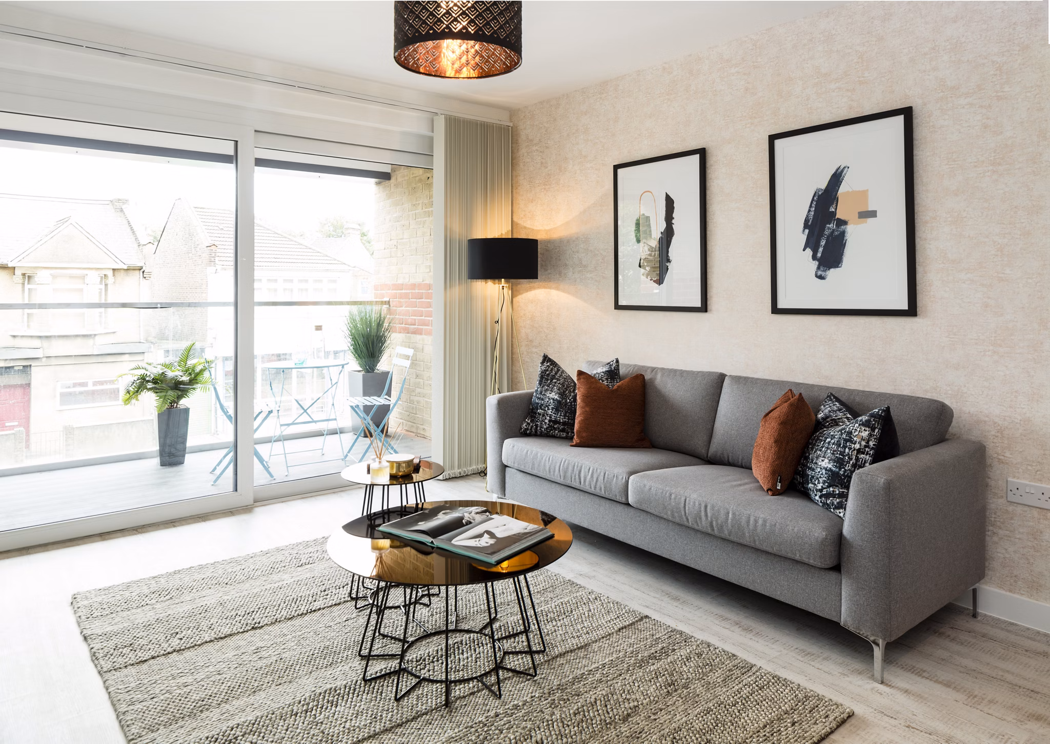 Modern living room in Fizzy Walthamstow apartments with a stylish gray sofa, coffee table, and large glass doors leading to a balcony.