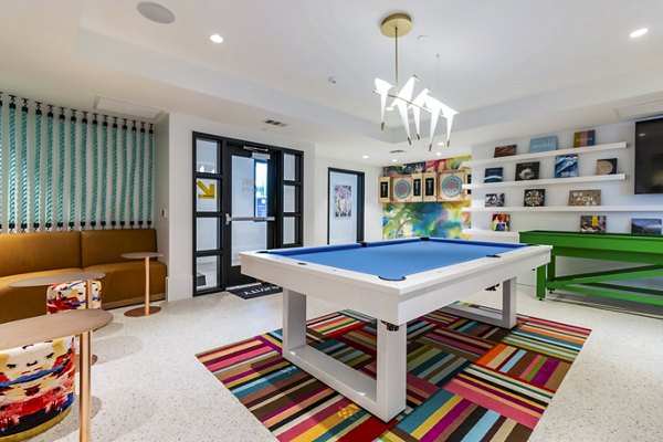 Gravity Apartments: Modern clubhouse game room with billiards table and lounge seating, perfect for entertaining guests