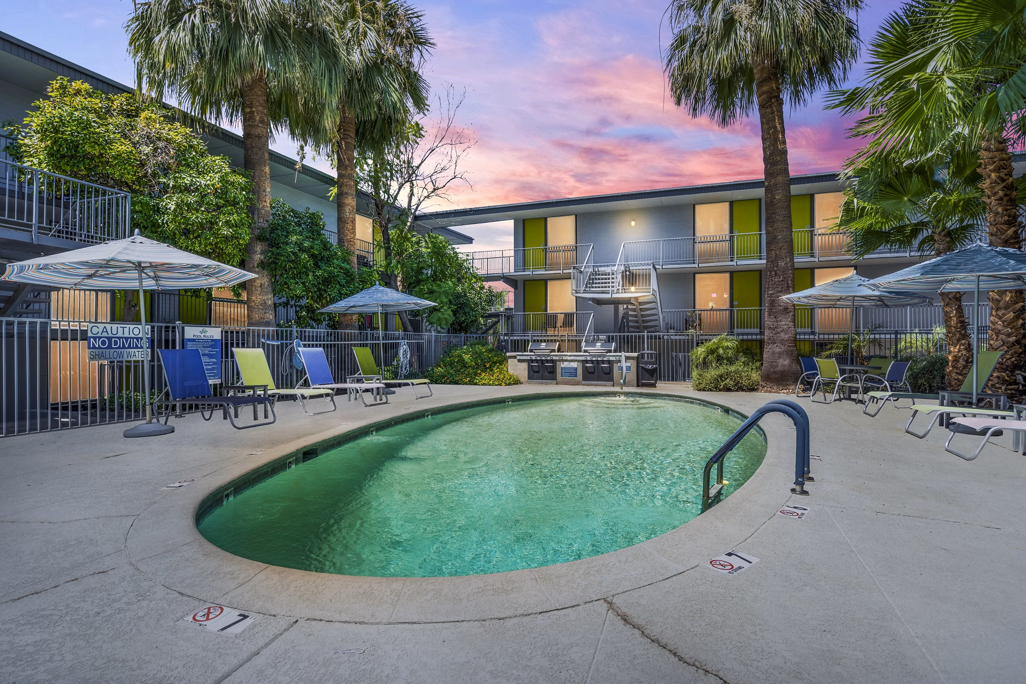Tranquil outdoor pool area at Crosstown Phoenix West Apartments with lounge seating and lush landscaping
