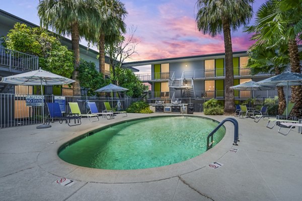 Tranquil outdoor pool area at Crosstown Phoenix West Apartments with lounge seating and lush landscaping