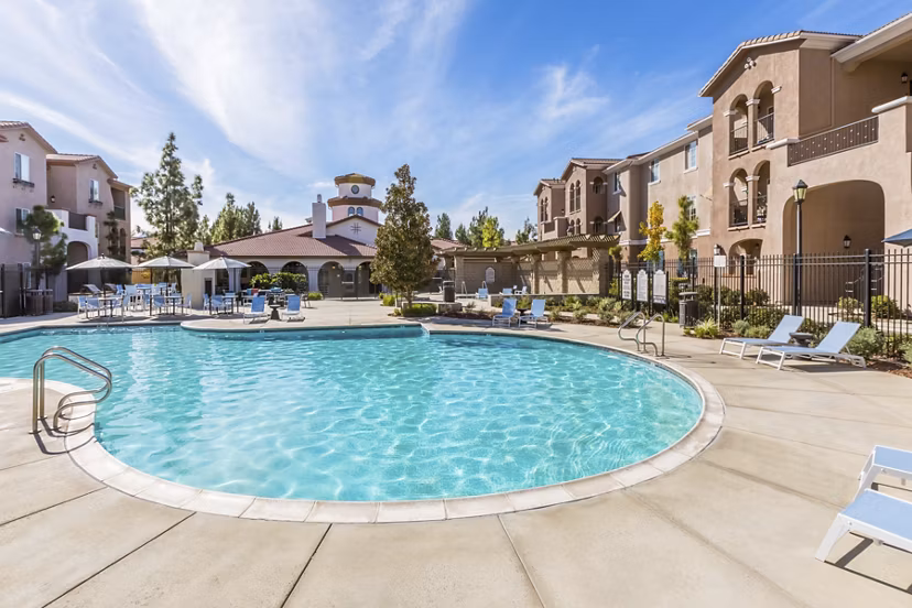 Outdoor pool surrounded by lush landscaping at Viano at Riverwalk Apartments, offering a relaxing retreat in a luxurious setting