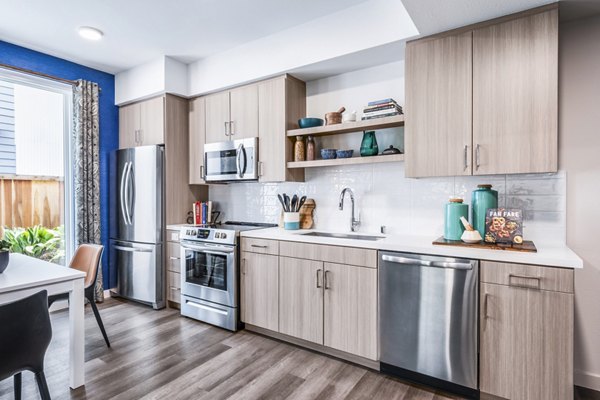 Modern kitchen with stainless steel appliances at Cora Apartments, offering luxury living with spacious countertops and sleek cabinetry