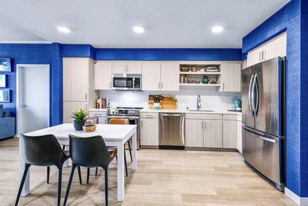 Modern kitchen with stainless steel appliances and granite countertops in Cora Apartments