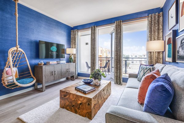 Elegant living room with stylish decor at Cora Apartments, featuring plush seating and abundant natural light