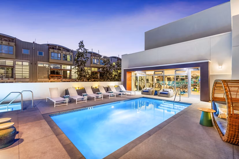 Cora Apartments: Luxury pool with designer lounge chairs and lush landscaping for relaxation and recreation