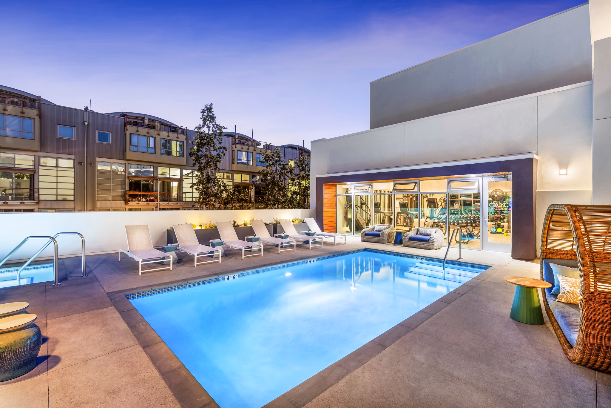 Cora Apartments: Luxury pool with designer lounge chairs and lush landscaping for relaxation and recreation