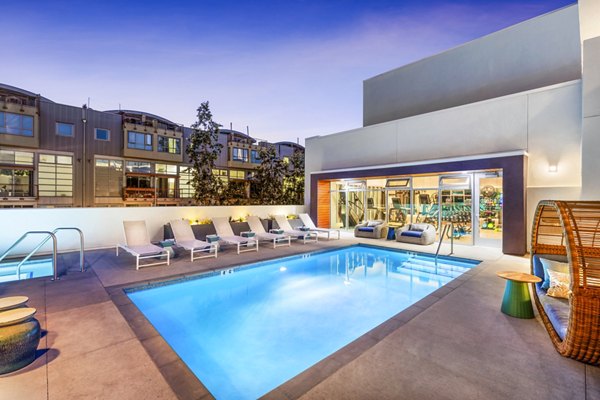 Cora Apartments: Luxury pool with designer lounge chairs and lush landscaping for relaxation and recreation