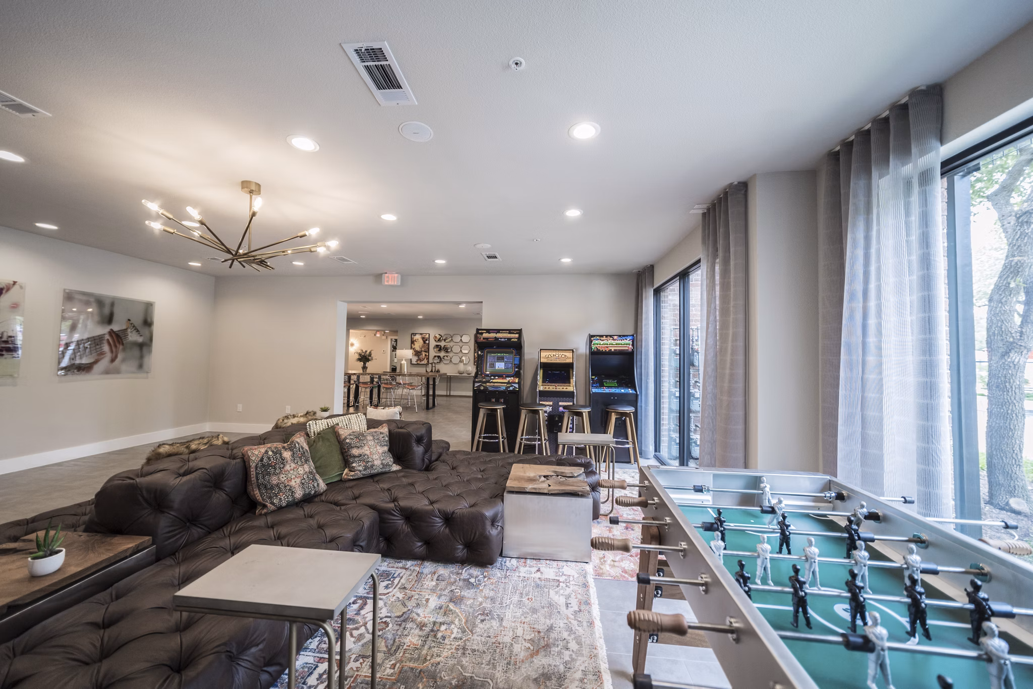Lounge area featuring a large sofa, arcade machines, and foosball table in luxury apartments