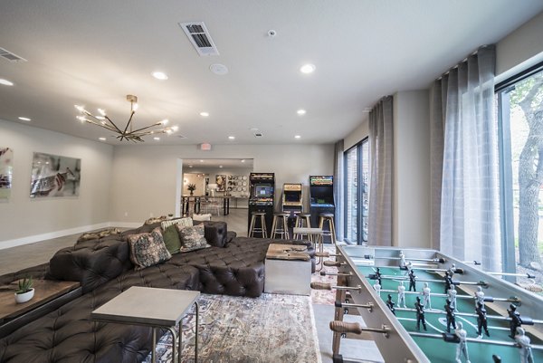 Lounge area featuring a large sofa, arcade machines, and foosball table in luxury apartments