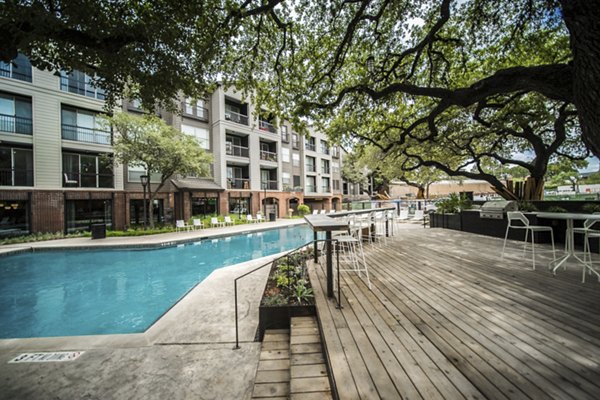 Luxurious poolside oasis at Muse at SoCo Apartments with chaise lounges and palm trees, perfect for relaxation and entertainment