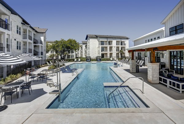 Sparkling outdoor pool at Leander Park Apartments with poolside lounge area for relaxation and recreation
