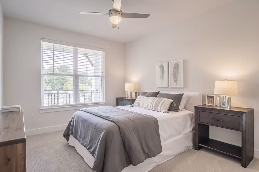 Cozy bedroom with elegant decor at The Heron at River Island Apartments, featuring a serene view