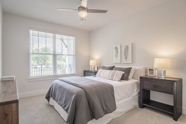 Cozy bedroom with elegant decor at The Heron at River Island Apartments, featuring a serene view