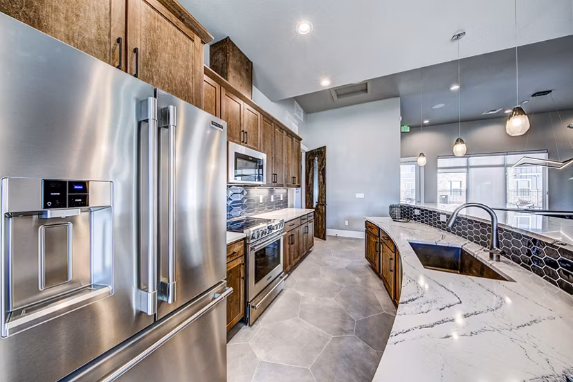 Clubhouse kitchen featuring modern appliances and island seating at The Bend at Highland Meadows Apartments