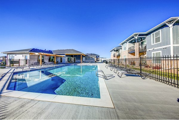 Resort-style pool at The Bend at Highland Meadows Apartments with relaxing lounge chairs and lush landscaping