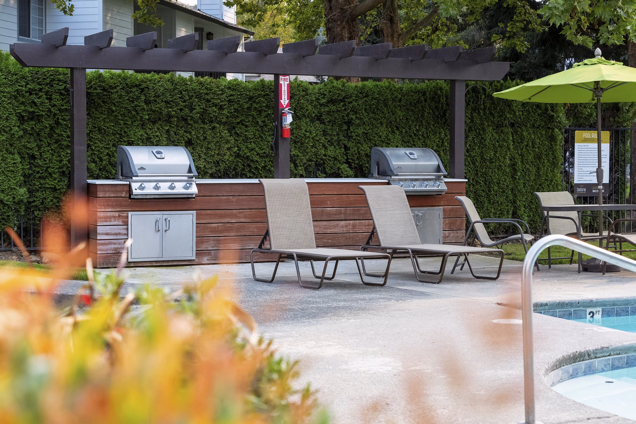 Grill area with modern seating and lush landscaping at Sedona at Bridgecreek Apartments