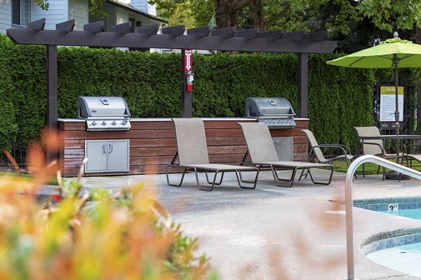 Grill area with modern seating and lush landscaping at Sedona at Bridgecreek Apartments