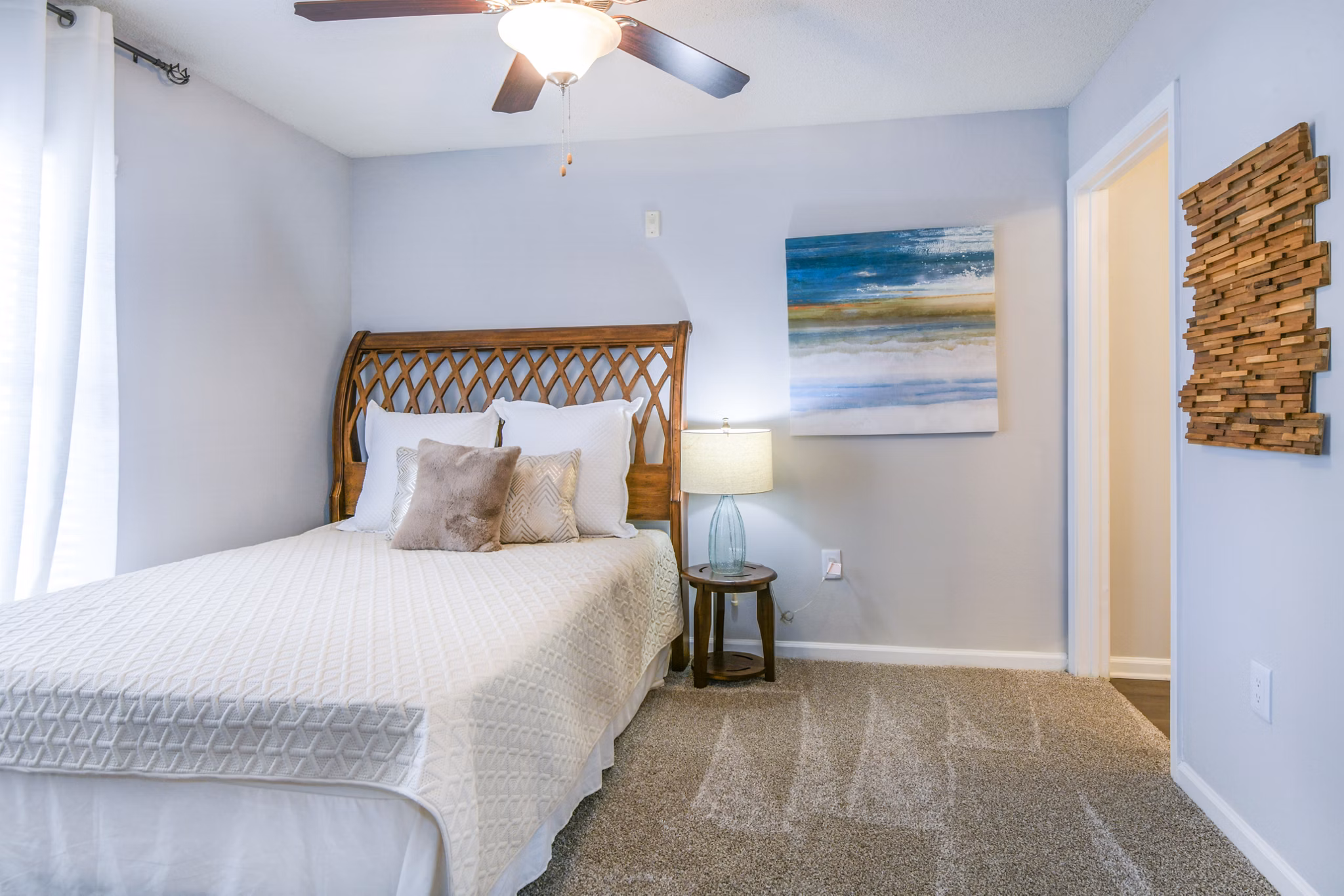 Cozy bedroom with a comfortable bed, decorative pillows, lamp, and ceiling fan in luxury apartment