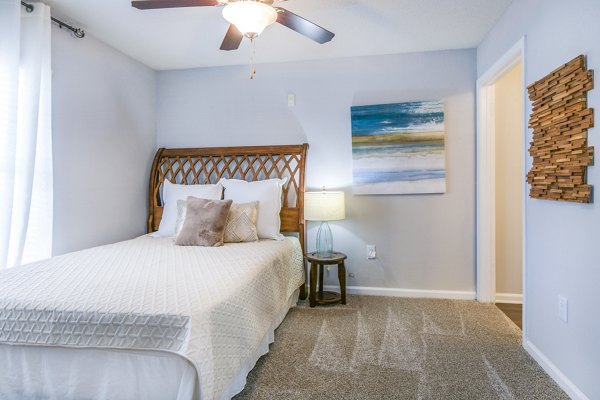 Cozy bedroom with a comfortable bed, decorative pillows, lamp, and ceiling fan in luxury apartment