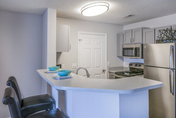 Modern kitchen featuring a bar counter with two stools and stainless steel appliances in luxury apartment